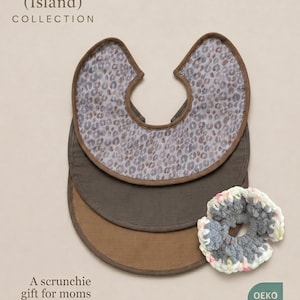 Pode incluir: Coleção ADA (Ilha). Três babadores para bebês em tons de marrom, com um babador superior com estampa de leopardo. Uma scrunchie cinza e branca está ao lado dos babadores. O texto diz "Um presente scrunchie para mães."