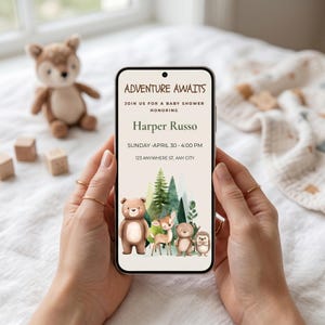 May include: A smartphone displays a baby shower invitation with the text "Adventure Awaits." The invitation features watercolor illustrations of a bear, deer, and other forest animals. The date and time are listed as Sunday, April 30, 4:00 PM.