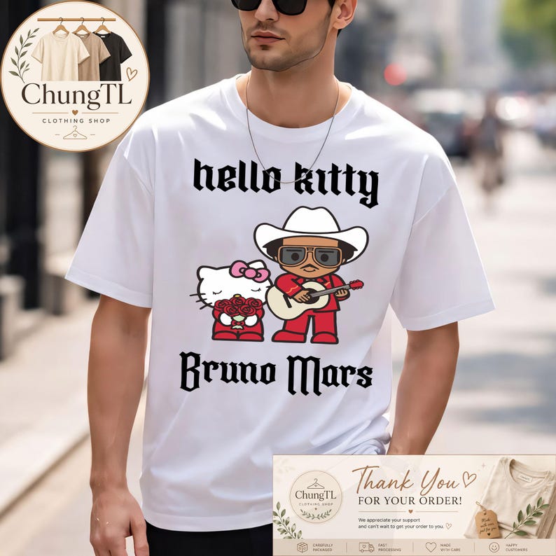 Peut inclure: T-shirt blanc avec un motif de Hello Kitty et Bruno Mars portant un chapeau de cowboy et jouant de la guitare. Les mots "hello kitty" et "Bruno Mars" sont imprim&eacute;s en noir. Le t-shirt est de ChungTL Clothing Shop.