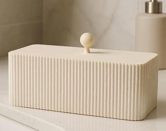 Op de afbeelding: Een rechthoekige, gebroken witte opbergdoos met een geribbelde, verticale textuur aan alle zijden. De doos heeft een plat, afneembaar deksel met een kleine, centraal geplaatste, bolvormige knop als handvat. Het ontwerp is uniform.