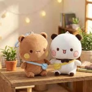 May include: Two plush bear-like toys, one brown and one white, stand on a wooden surface. The brown bear has a blue bag, while the white bear has a yellow bag. Both have rosy cheeks and small, cute features. The background includes plants and soft lighting.