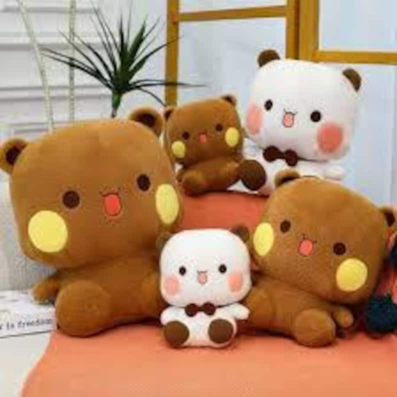 May include: A collection of plush bear toys in various sizes and colors. The bears have brown and white fur, with yellow cheek accents, and small bow ties. Some bears are sitting, while others are lying down. The background includes a window and a plant.