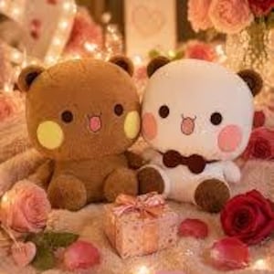May include: Two plush bear toys, one brown and one white, with rosy cheeks and small tongues sticking out. A small gift box with a pink bow sits between them, surrounded by rose petals and fairy lights. The bears have brown ears and black eyes.
