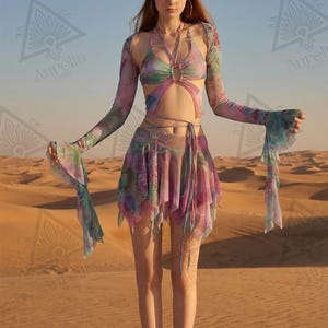 May include: A multi-coloured tie-dye mesh two-piece set featuring a halter-style crop top with long flared sleeves and a matching asymmetrical mini skirt with wrap-around waist ties. The fabric displays a blend of pink, purple, blue, and green hues.