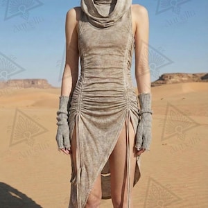 Könnte beinhalten: Ein ärmelloses Kapuzenkleid aus beigem, verwaschenem Stoff mit Wasserfallausschnitt, gerafften Seitenteilen mit langen, herabhängenden Bändern und hohen Beinschlitzen. Das Kleid wird mit passenden gerippten, fingerlosen Armstulpen kombiniert.