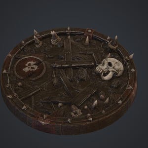 Könnte beinhalten: Ein runder brauner Schild mit einer Oberfläche aus dunklen Holzplanken, einem markanten cremefarbenen menschlichen Schädel und einem kleinen runden Emblem mit einem weißen Totenkopf-Symbol. Der äußere Rand ist mit dunklen Metallbändern verstärkt.