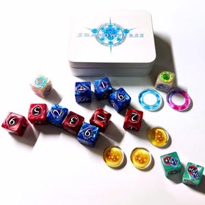 Könnte beinhalten: Eine weiße, rechteckige Aufbewahrungsdose aus Metall mit dem aufgedruckten Shadowverse-Logo auf dem Deckel, begleitet von einer Sammlung mehrfarbiger sechsseitiger Würfel mit Zahlen und Symbolen sowie mehreren durchscheinenden runden Spielmarken.