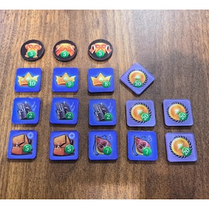 May include: A collection of game tokens including three black circular pieces with a number 5, three blue square pieces with crowns numbered 10, 9, and 8, three blue squares with gloves numbered 2, three blue squares with bags numbered 5, 7, and 7, and four purple diamond or square tokens with gold coins numbered 20.