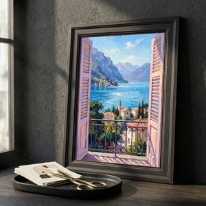 May include: A framed painting depicts a scenic view through an open window with pink shutters. The artwork showcases a serene landscape with a lake, mountains, and buildings. A black tray with cards and gold scissors sits in front of the painting.