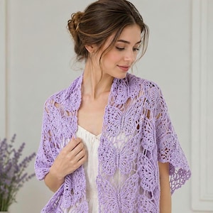 May include: A light purple, open-weave shawl with a butterfly design. The shawl is crocheted and drapes over the shoulders. The butterfly pattern is repeated throughout the shawl. The woman in the image is wearing a white top.