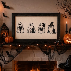 May include: A rectangular cross-stitch embroidery in a black frame featuring four pixel-art style ghosts on a light fabric background. Each ghost is depicted in black thread, with three ghosts holding black cats and one ghost wearing a witch hat.