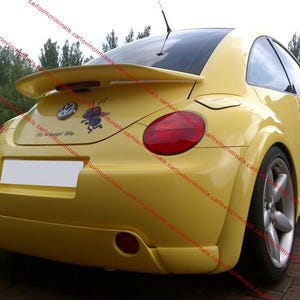 Peut inclure: Une Volkswagen Beetle jaune vif vue de l'arrière, dotée d'un aileron arrière, de jantes en alliage argentées et d'un petit autocollant représentant une fourmi avec le texte "it's a bug's life" près de l'emblème circulaire Volkswagen sur le coffre.