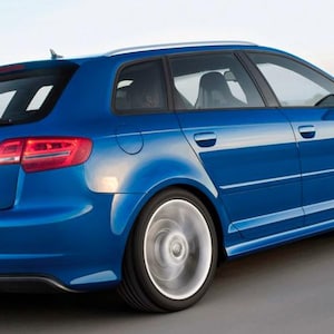 Könnte beinhalten: Ein hellblauer Audi Schrägheckwagen in der Dreiviertelansicht von hinten. Das Fahrzeug verfügt über einen Heckspoiler, getönte Scheiben, silberne Leichtmetallfelgen in Bewegung und das Audi-Logo mittig auf der Heckklappe über einem weißen Kennzeichen.