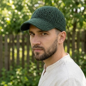 May include: A dark forest green baseball cap constructed from crocheted yarn. The cap features a structured crown with a visible stitch pattern and a curved brim, showcasing a handmade textile design with a consistent deep green color throughout.