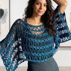 May include: A teal blue, open-weave crochet poncho. The poncho features a round neckline and flared sleeves. The crochet pattern creates a textured, airy design. The garment is worn over a dark gray top.