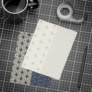 May include: Two rectangular paper sheets featuring geometric patterns. One sheet displays a dark blue hemp leaf design on a light background. The other sheet shows a light blue starburst pattern on the left and a wave pattern on the right.