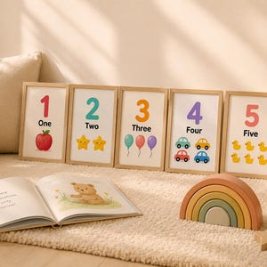 May include: Five framed number prints with illustrations of an apple, stars, balloons, cars, and ducks. A wooden rainbow stacker, open book, and star-shaped toy are also visible. The prints display the numbers one through five.