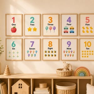 May include: A set of ten framed number prints, each featuring a number from one to ten with corresponding illustrations. The prints have a neutral background and are displayed on a light-colored wall. The illustrations include an apple, stars, balloons, cars, ducks, flowers, bees, ice cream cones, and stars.