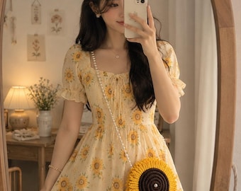 May include: A light yellow dress featuring a repeating sunflower pattern, short puff sleeves, and a square neckline. The dress is paired with a round, crocheted sunflower-shaped crossbody bag with a white pearl-style beaded strap.