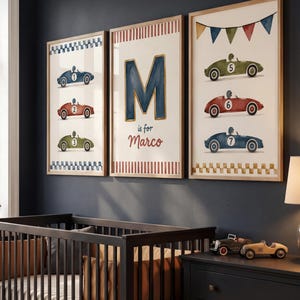 Pode incluir: Três impressões emolduradas em aquarela com carros de corrida vintage em azul, vermelho e verde. A impressão do meio tem uma grande letra "M" azul e o texto "is for Marco". As impressões são exibidas acima de um berço escuro em um berçário.