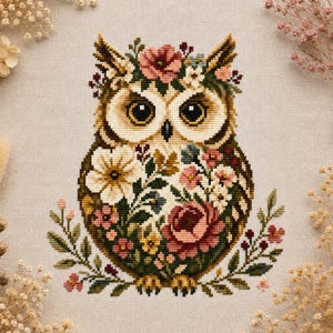 Puede incluir: Un bordado de punto de cruz sobre tela de color beige claro con un diseño central de un búho. El búho está decorado con varios patrones florales en tonos rosa, rojo, blanco y verde, con grandes ojos oscuros y detalles de plumas.