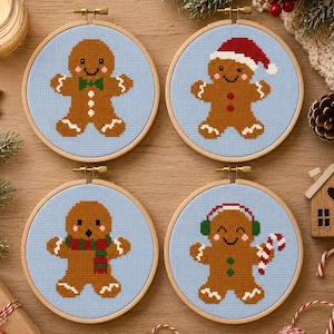 Pode incluir: Quatro bastidores de bordado circulares com personagens de pão de mel em ponto cruz sobre tecido azul claro. Um usa uma gravata borboleta verde, um gorro de Papai Noel vermelho, um cachecol vermelho e verde e protetores de ouvido verdes.
