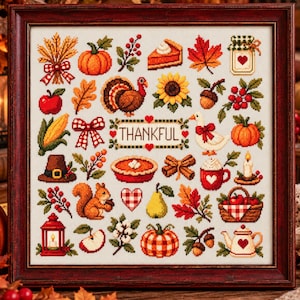 May include: A framed cross-stitch sampler featuring a grid of autumn-themed icons including pumpkins, a turkey, a squirrel, leaves, a pie, and a mug, with the word THANKFUL centred in a decorative border. The design uses warm fall colours.