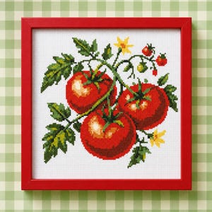 May include: A square cross-stitch embroidery featuring three ripe red tomatoes on a vine with green leaves and small yellow flowers, enclosed in a bright red wooden frame. The design is stitched on white fabric with visible grid texture.