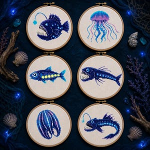 Puede incluir: Seis bastidores de bordado circulares de madera con patrones de punto de cruz de criaturas de las profundidades marinas. Los diseños incluyen un rape bioluminiscente, una medusa, un pez pequeño, un pez dragón, un ctenóforo y otro rape.
