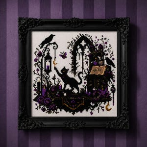 May include: A framed cross-stitch embroidery featuring a black cat reaching for a crescent moon, a raven, a lantern, an open book, and purple floral accents. The design is rendered in black and purple thread on a white fabric background.
