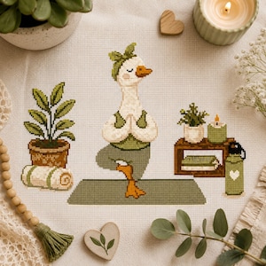 May include: A cross-stitch pattern on light fabric featuring a white goose with an orange beak wearing a green headband and top, performing a yoga tree pose on a green mat. The scene includes a potted plant, a rolled towel, and a small shelf.