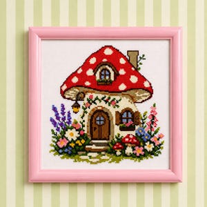 May include: A cross-stitch embroidery in a pink frame depicting a house shaped like a red mushroom with white spots. The house features a brown door, windows, and a chimney, surrounded by colorful flowers, green foliage, and smaller mushrooms.