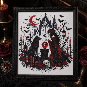 May include: Cross-stitch art in a black frame. The design features a gothic scene with a figure in a red cloak, a wolf, a crescent moon, bats, and a castle. Red roses, candles, and a skull add to the dark aesthetic.