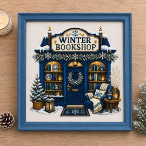 Può includere: Un ricamo a punto croce incorniciato che raffigura una vetrina blu con la scritta WINTER BOOKSHOP, con scaffali innevati, una porta centrale con ghirlanda, una poltrona accogliente con coperta, un piccolo albero di Natale e lanterne.