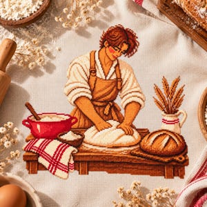 May include: A cross-stitch embroidery on light fabric depicting a person with brown hair wearing a tan apron, kneading dough on a wooden table. The scene includes a red bowl, a small bowl of flour, a loaf of bread, and a pitcher of wheat stalks.