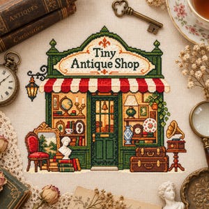 以下が含まれることがあります： Tiny Antique Shopという文字が刺繍されたクロスステッチの作品。緑色のファサード、赤と白のストライプのオーニング、地球儀や花瓶などのアンティーク品で満たされたショーウィンドウが描かれています。