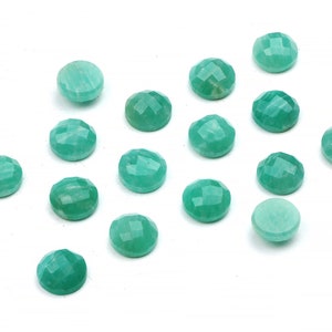 Peut inclure: Une collection de 15 cabochons de pierres pr&eacute;cieuses vertes, chacun avec une surface facet&eacute;e. Les cabochons sont dispos&eacute;s en un motif l&acirc;che sur un fond blanc.