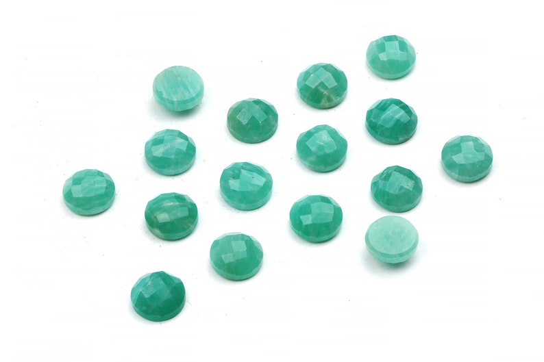 Peut inclure: Une collection de 15 cabochons de pierres pr&eacute;cieuses vertes, chacun avec une surface facet&eacute;e. Les cabochons sont dispos&eacute;s en un motif l&acirc;che sur un fond blanc.