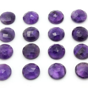 May include: Fifteen round, faceted amethyst gemstones in various shades of purple. The gemstones are arranged in a grid pattern on a white background.