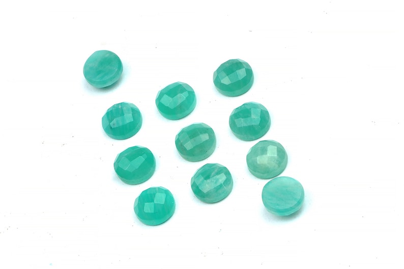 Peut inclure: Douze pierres pr&eacute;cieuses rondes, facett&eacute;es, de couleur vert turquoise. Les pierres pr&eacute;cieuses sont dispos&eacute;es en un motif l&acirc;che et dispers&eacute; sur une surface blanche.