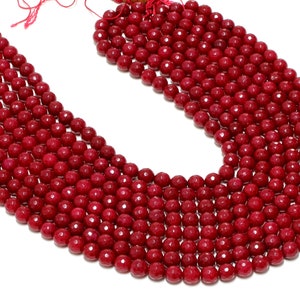 以下が含まれることがあります： 赤い宝石のビーズの糸。ビーズは丸くてファセットカットされており、細い紐に通されています。ビーズは円形に配置されており、すべて同じサイズです。