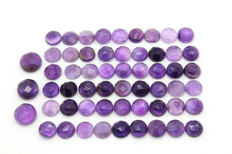 May include: A collection of 36 round, faceted amethyst gemstones. The stones are a deep purple color and have a smooth, polished finish.