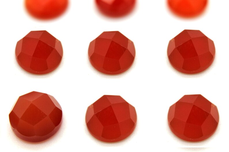 May include: Ten round, faceted carnelian gemstones in various shades of red.