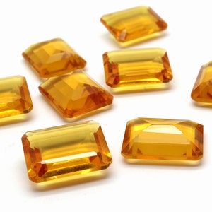 Peut inclure: Sept pierres précieuses rectangulaires, facettées, de couleur ambre. Les pierres précieuses sont disposées de manière dispersée sur un fond blanc.