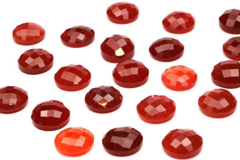 May include: A collection of 18 red, orange, and brown gemstone cabochons. The cabochons are faceted and have a smooth, polished finish.