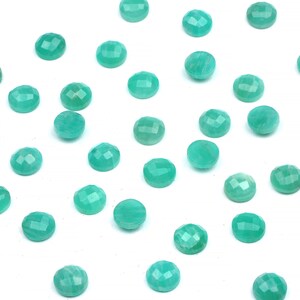 Peut inclure: Une collection de pierres pr&eacute;cieuses rondes, facett&eacute;es, vert turquoise sur un fond blanc.