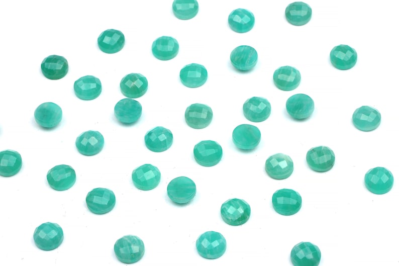 Peut inclure: Une collection de pierres pr&eacute;cieuses rondes, facett&eacute;es, vert turquoise sur un fond blanc.