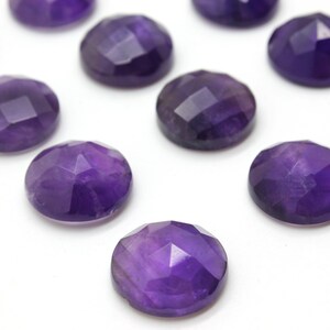 May include: A collection of twelve round, faceted amethyst gemstones. The gemstones are a deep purple color and have a smooth, polished finish.