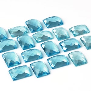 May include: A collection of 16 light blue, faceted, rectangular gemstones arranged in a staggered pattern on a white background.