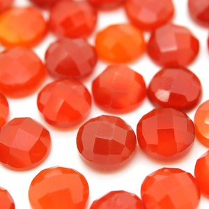 May include: A collection of smooth, round, red carnelian gemstones. The stones are faceted and have a polished finish.